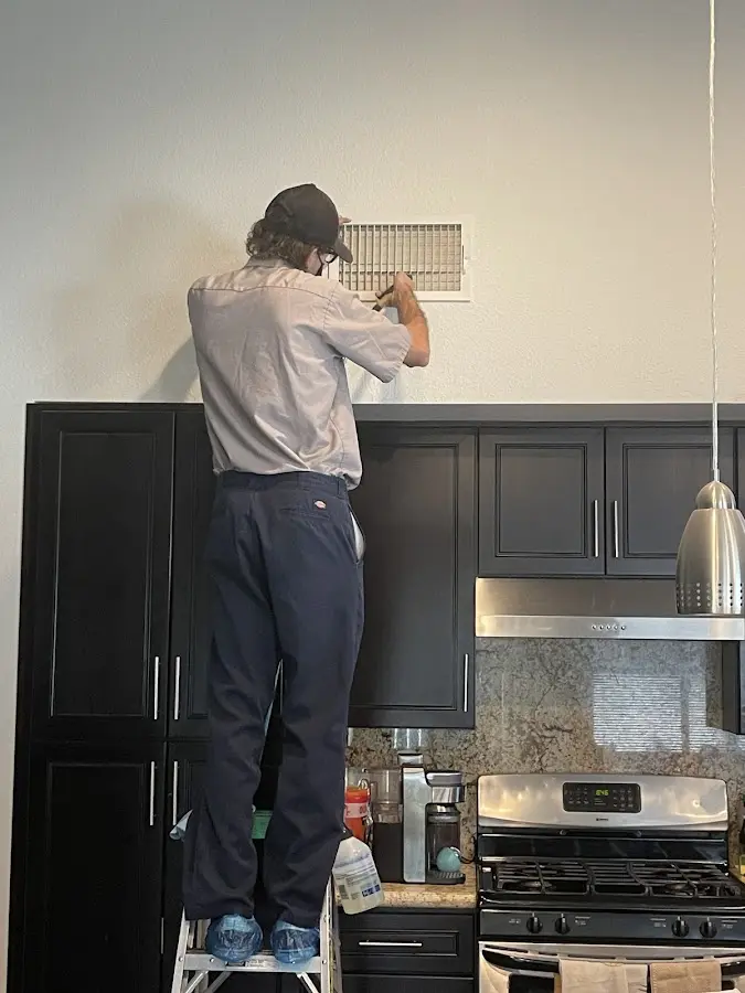 Technician inspecting an air vent during HVAC service in Rowley